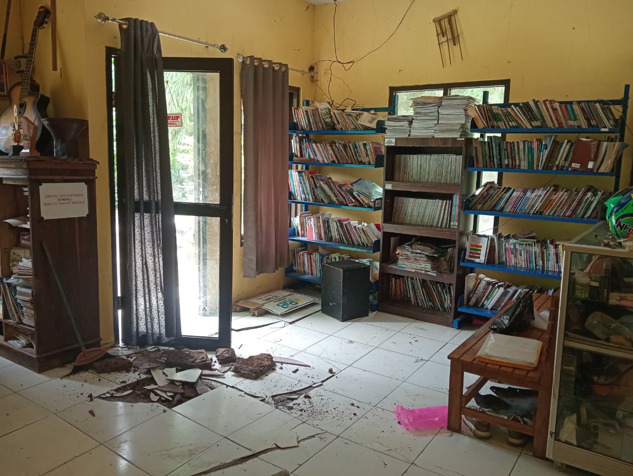 Kondisi perpustakaan pasca pergeseran tanah: Lantai keramik di dekat pintu masuk hancur dan terbelah, membuat bangunan tidak aman untuk kegiatan.