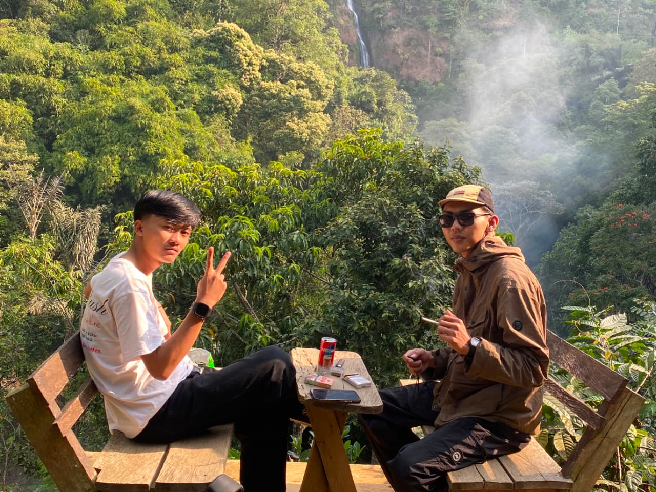 Wisatawan bersantai di spot foto jalur treking Desa Wisata Cibeusi, Ciater, Subang. Area ini menyuguhkan panorama perbukitan asri dengan latar aliran Curug Cibareubeuy dari kejauhan. (Foto: Dok. daridesa.com)